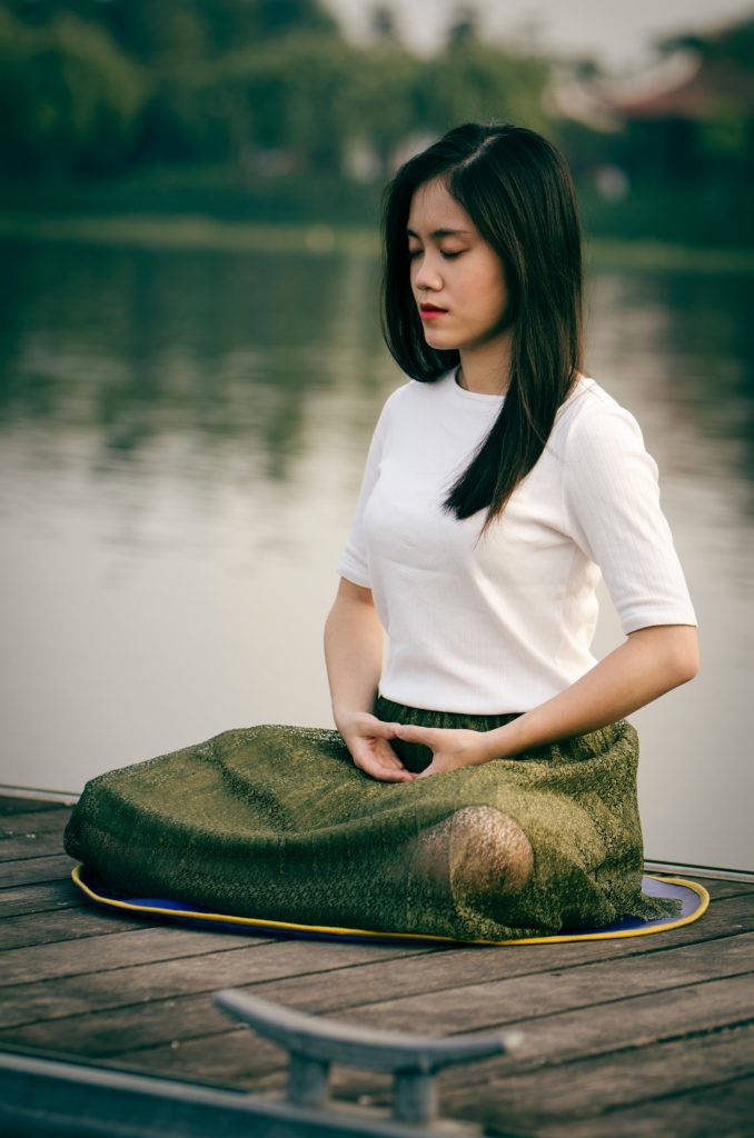 Mujer meditando con un lago detrás